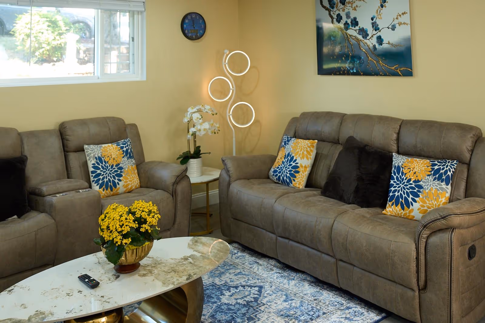 Cozy beige living room with cushioned sofas, colorful pillows, coffee table, and wall art.