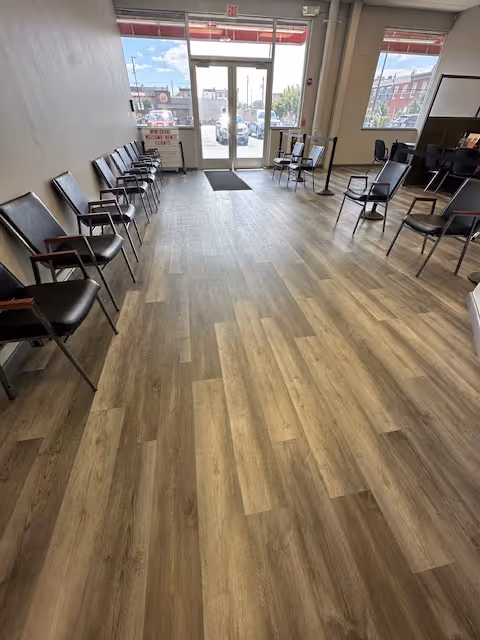 A narrow interior waiting area with chairs along the walls and a glass front door.