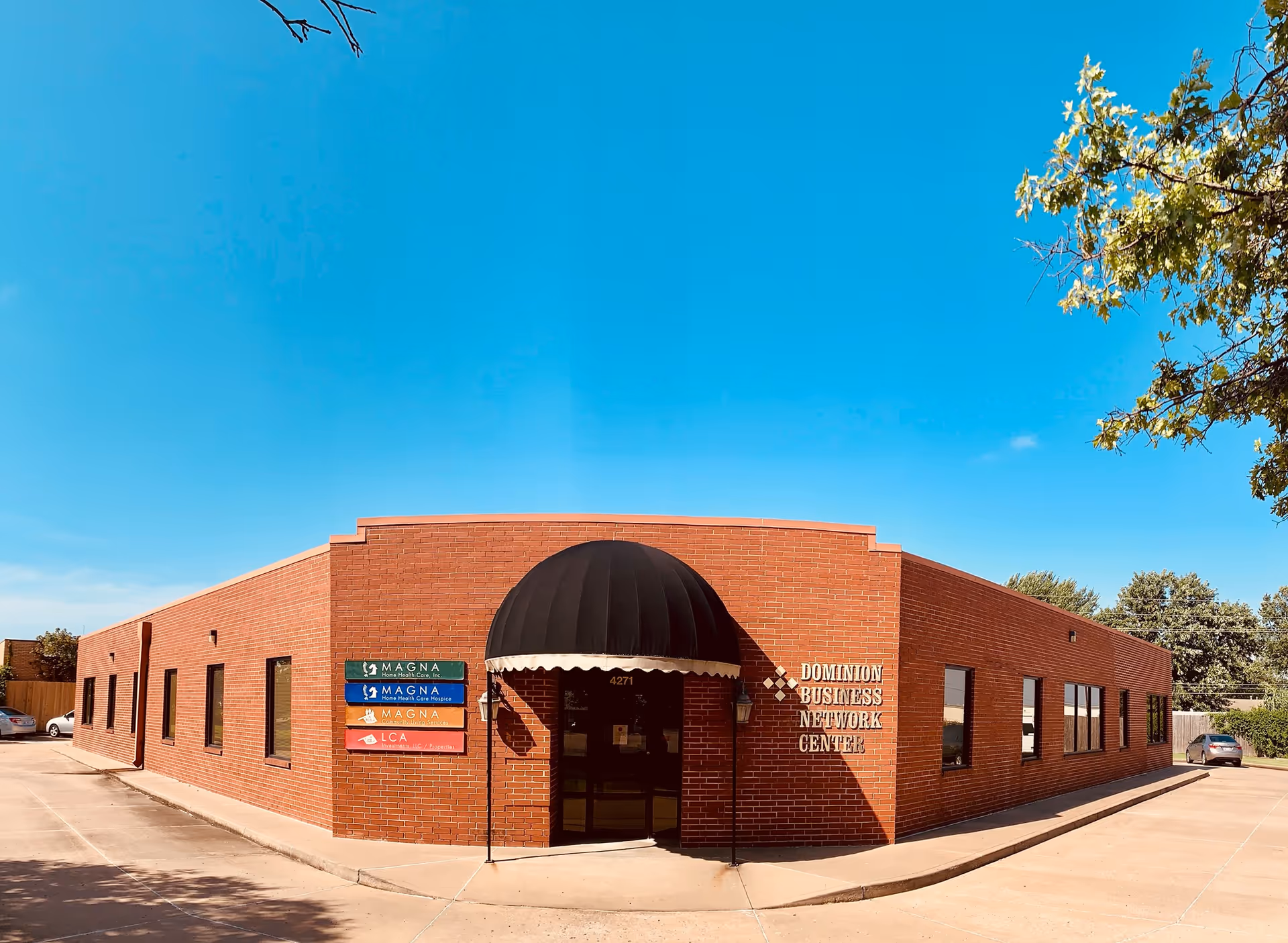 Brick one-story building with a black domed entrance awning and glass doors.