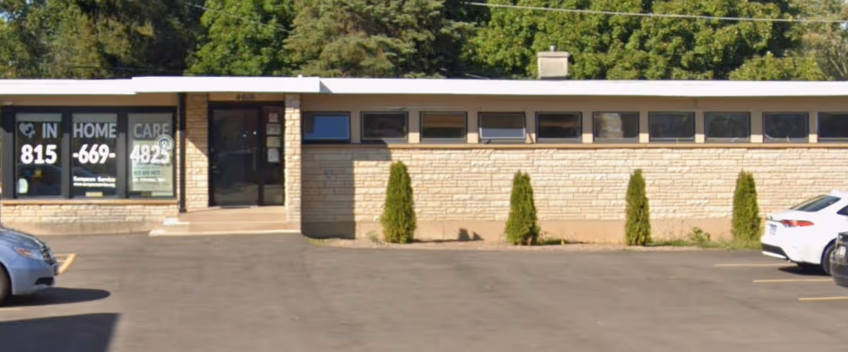 Exterior view of a single-story senior care building with a parking lot and shrubs.