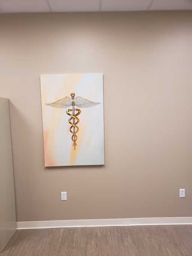 Beige interior wall with a large medical caduceus artwork hung between outlets.
