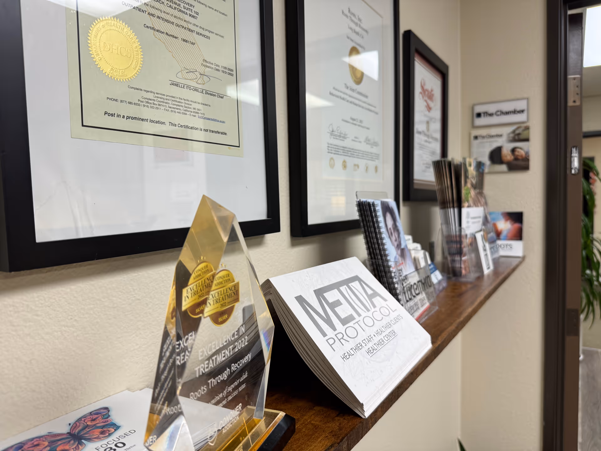 Interior hallway with framed certificates and brochures on a wooden reception counter.