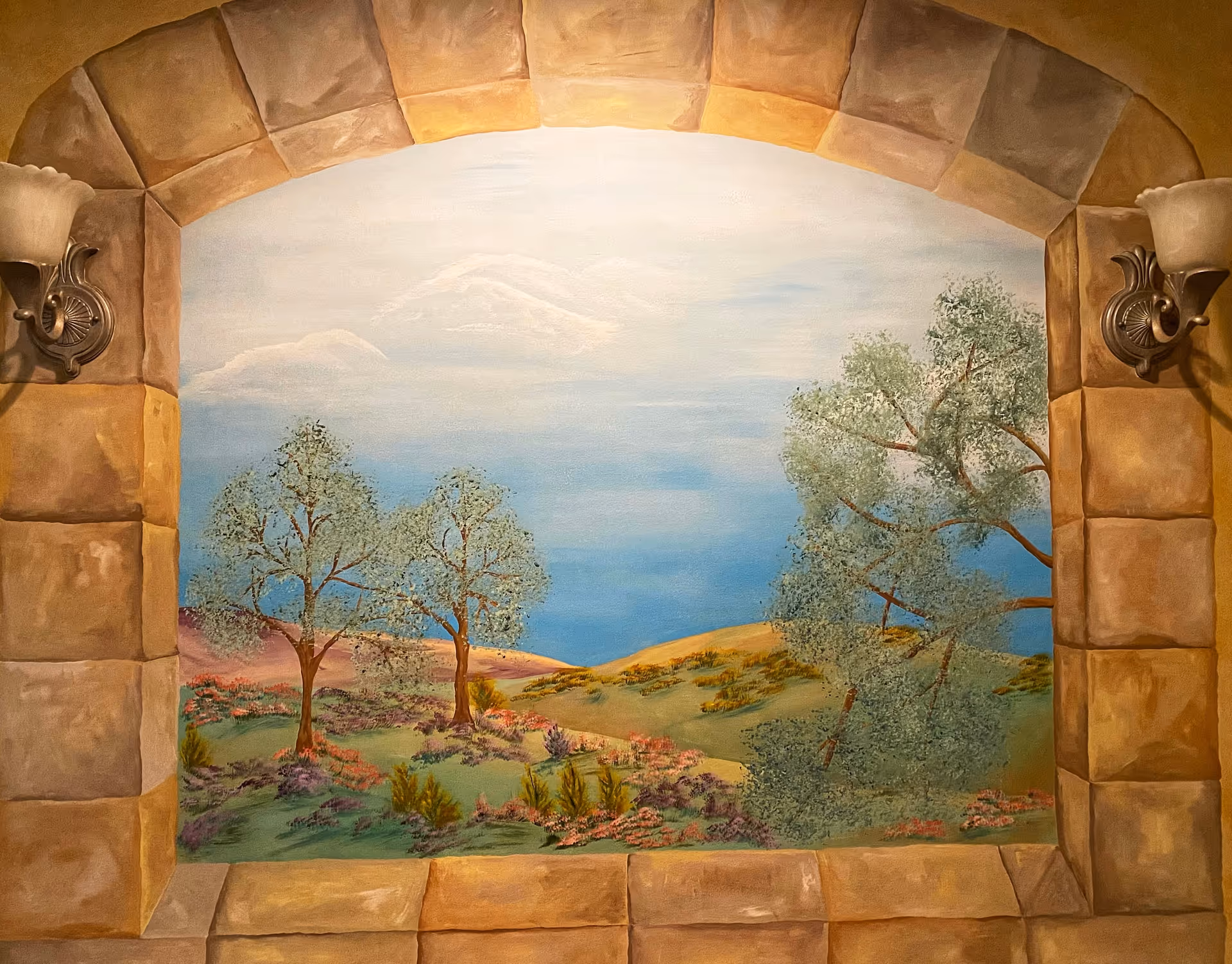 Stone archway interior with a large painted landscape mural featuring trees and hills.