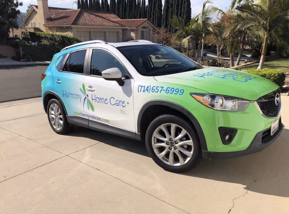Harmony Home Care branded SUV parked on a driveway with a suburban home behind.