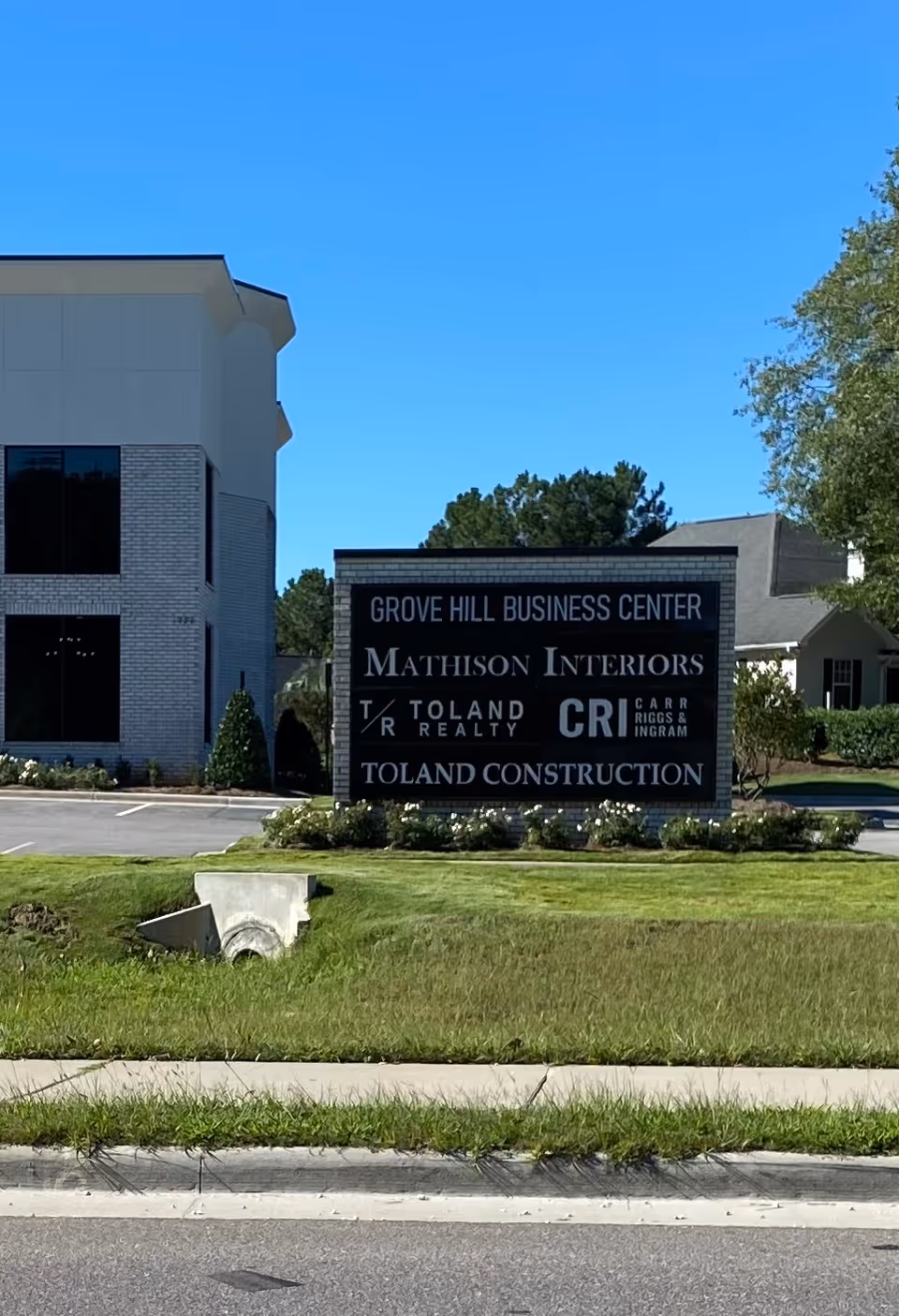 Exterior view of a modern building with a large sign in a landscaped front yard.