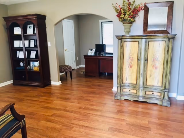 A spacious lobby area with wood floors, an archway, a cabinet, and a bookshelf.
