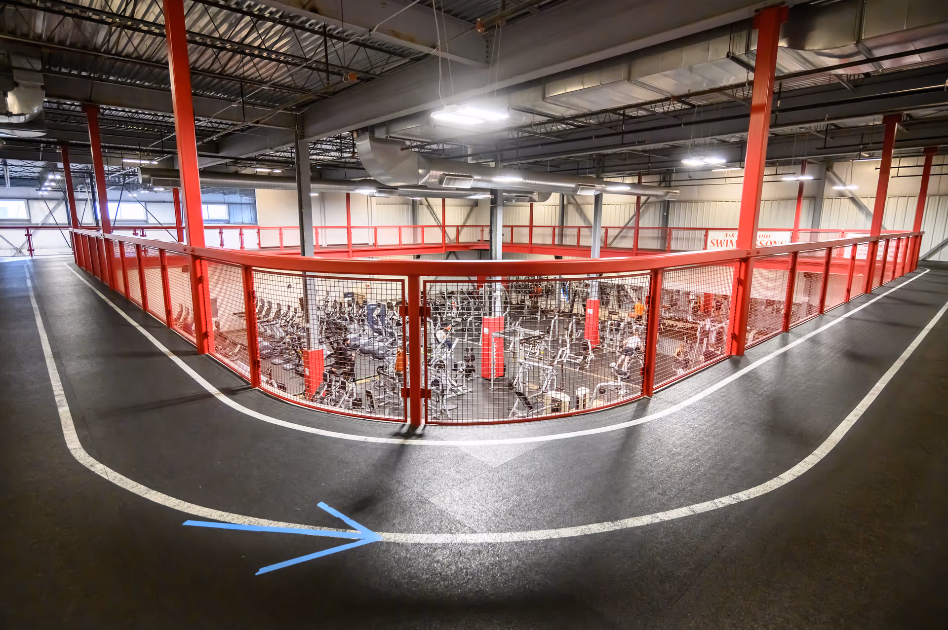 Indoor gym area with circular red railing surrounding exercise bikes and equipment.