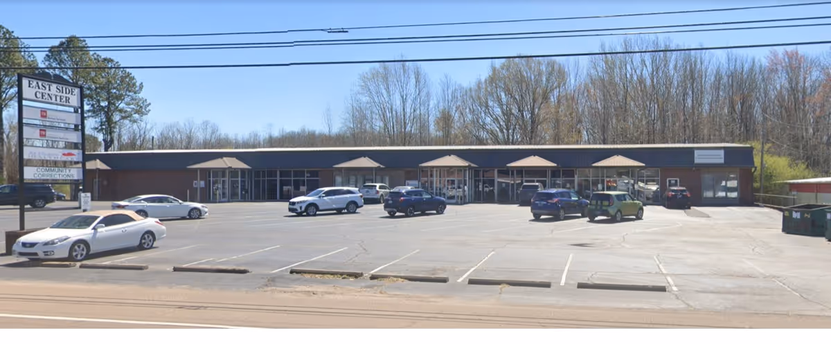 Commercial single-story brick building with glass doors, East Side Center sign, and parked cars.