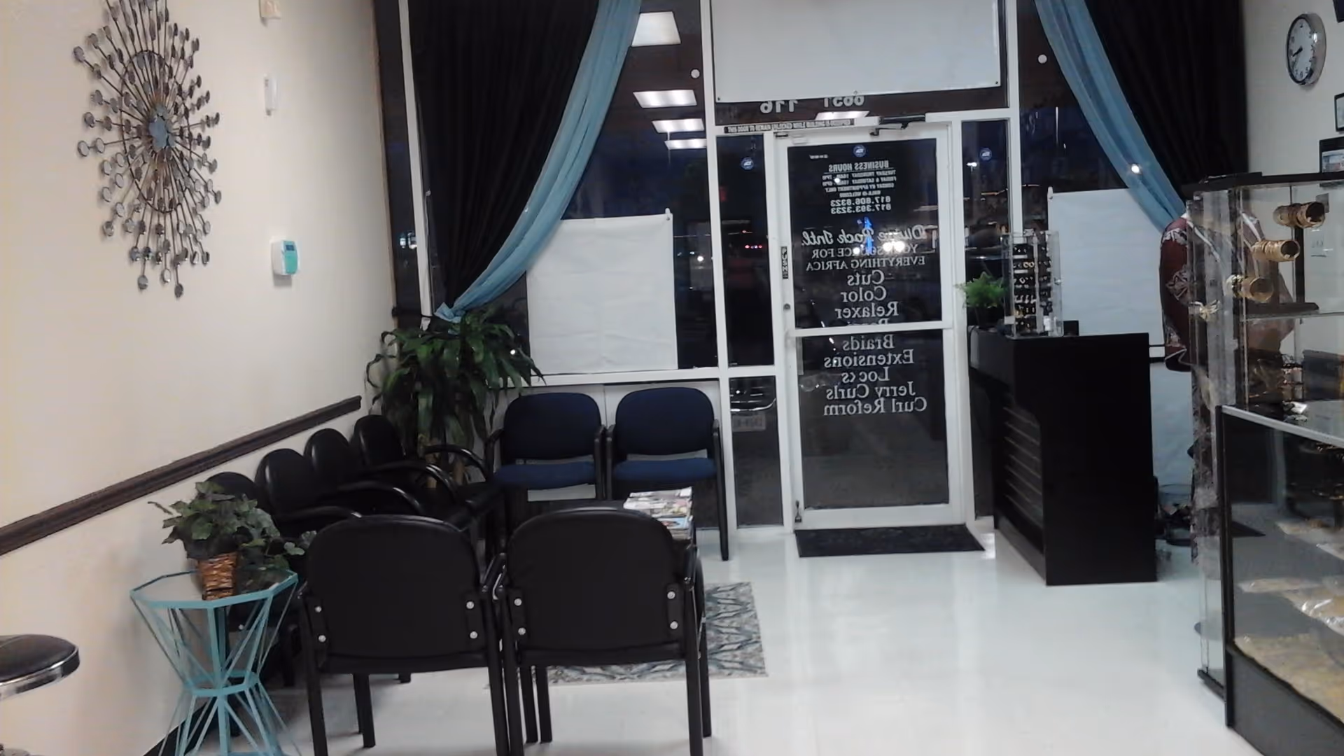 A clean, modern facility lobby with black chairs, blue curtains, plants, and a glass entrance.