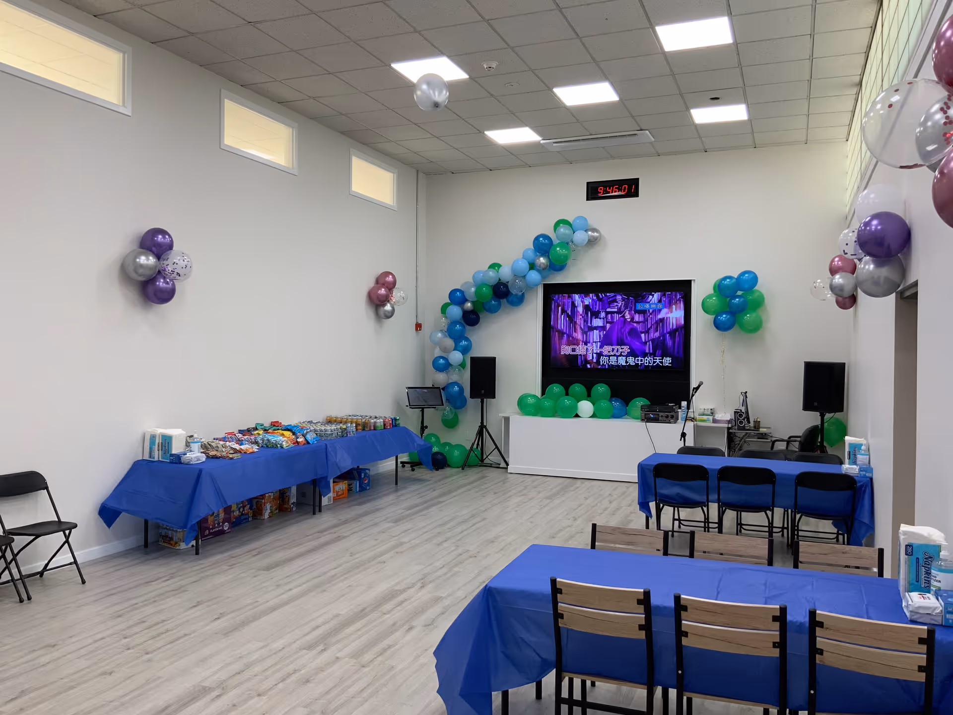 Decorated event room with balloons, tables, and a television screen in a senior facility.