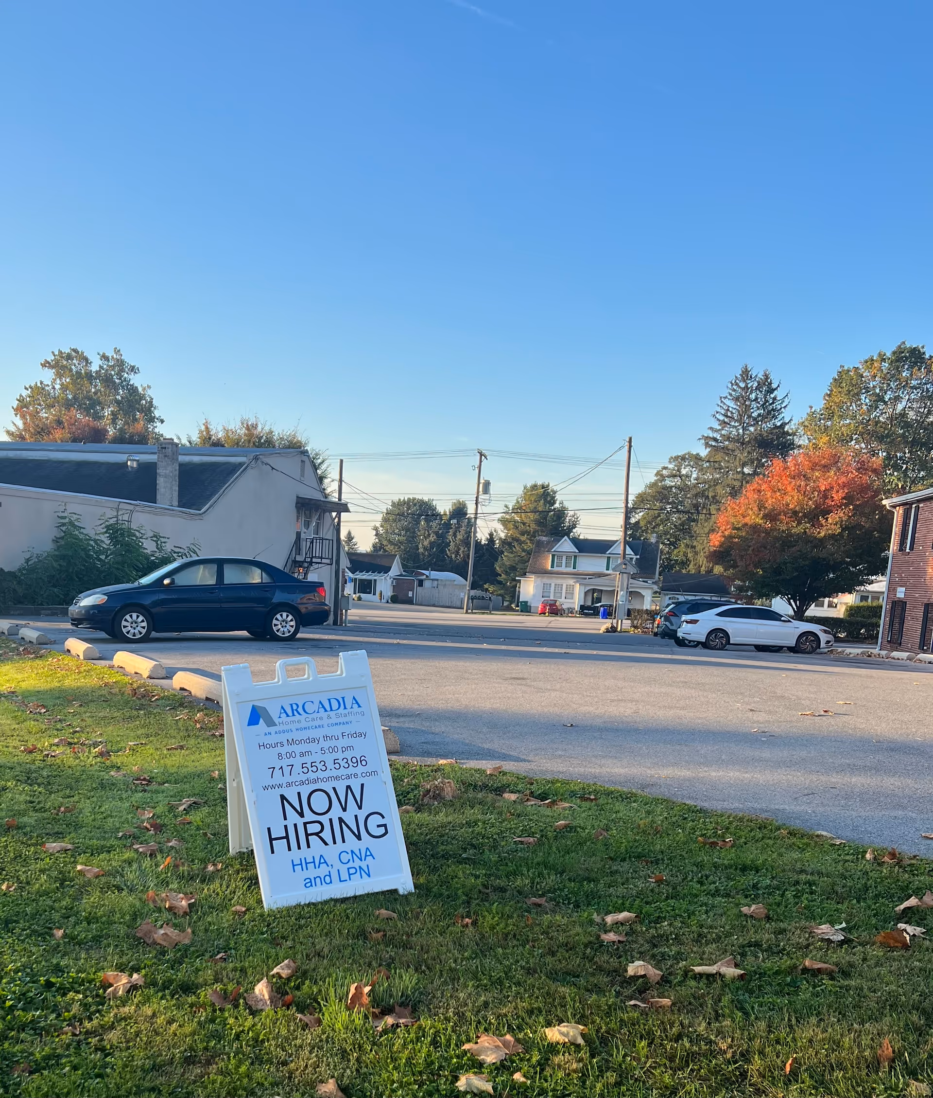 Exterior street view of Arcadia Home Care and Staffing with a Now Hiring sign on grass