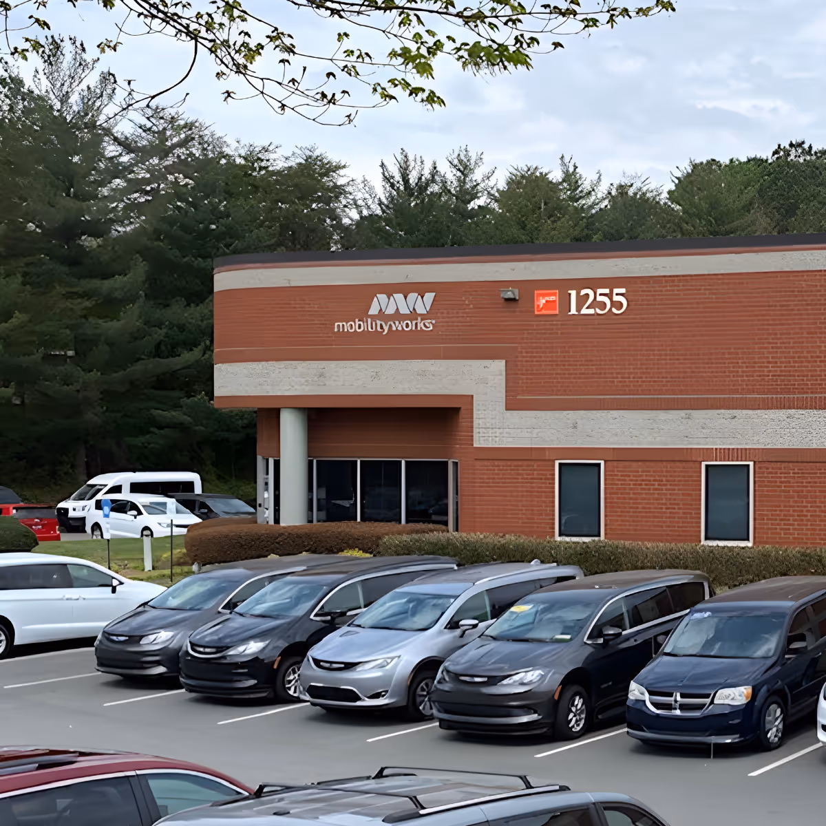 MobilityWorks building with brick exterior and a parking lot full of cars.