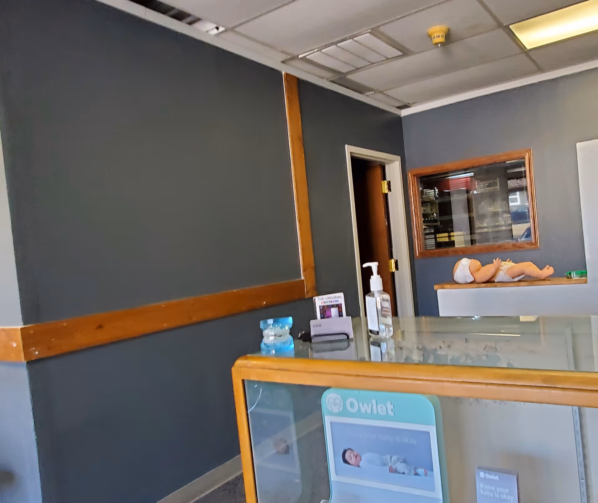 Interior reception area with dark blue walls, doorway, counter, and a CPR manikin on a shelf.