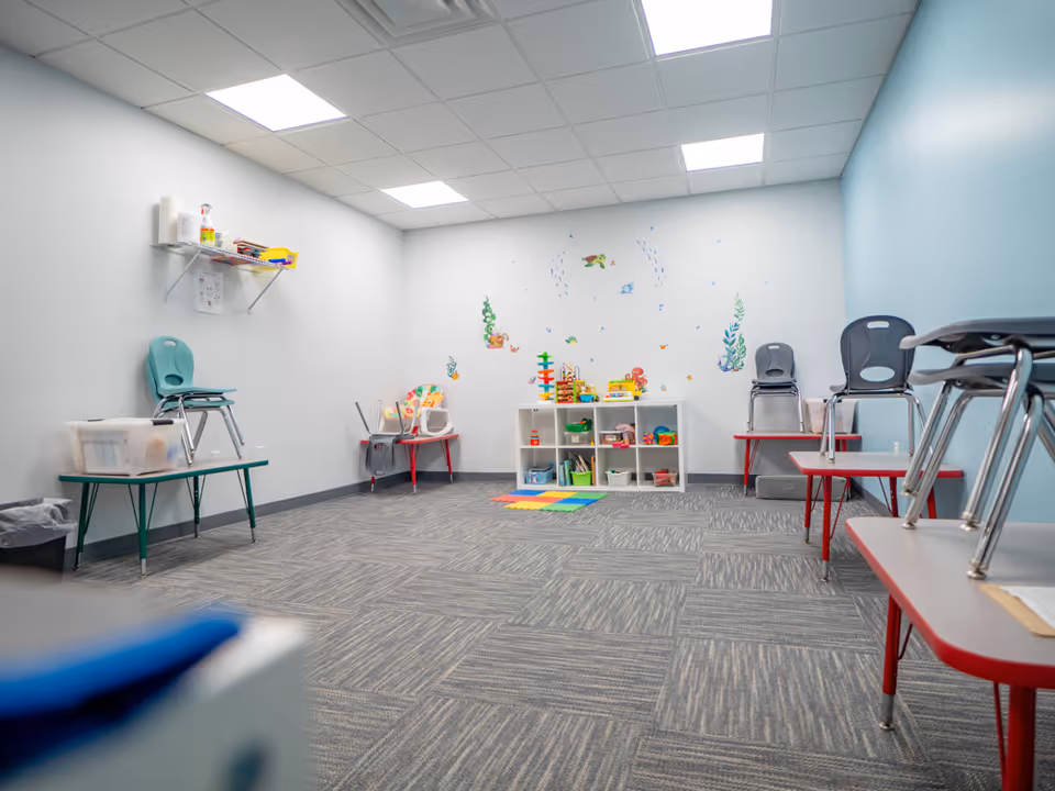 Small playroom with toys, shelves, and colorful wall decals.