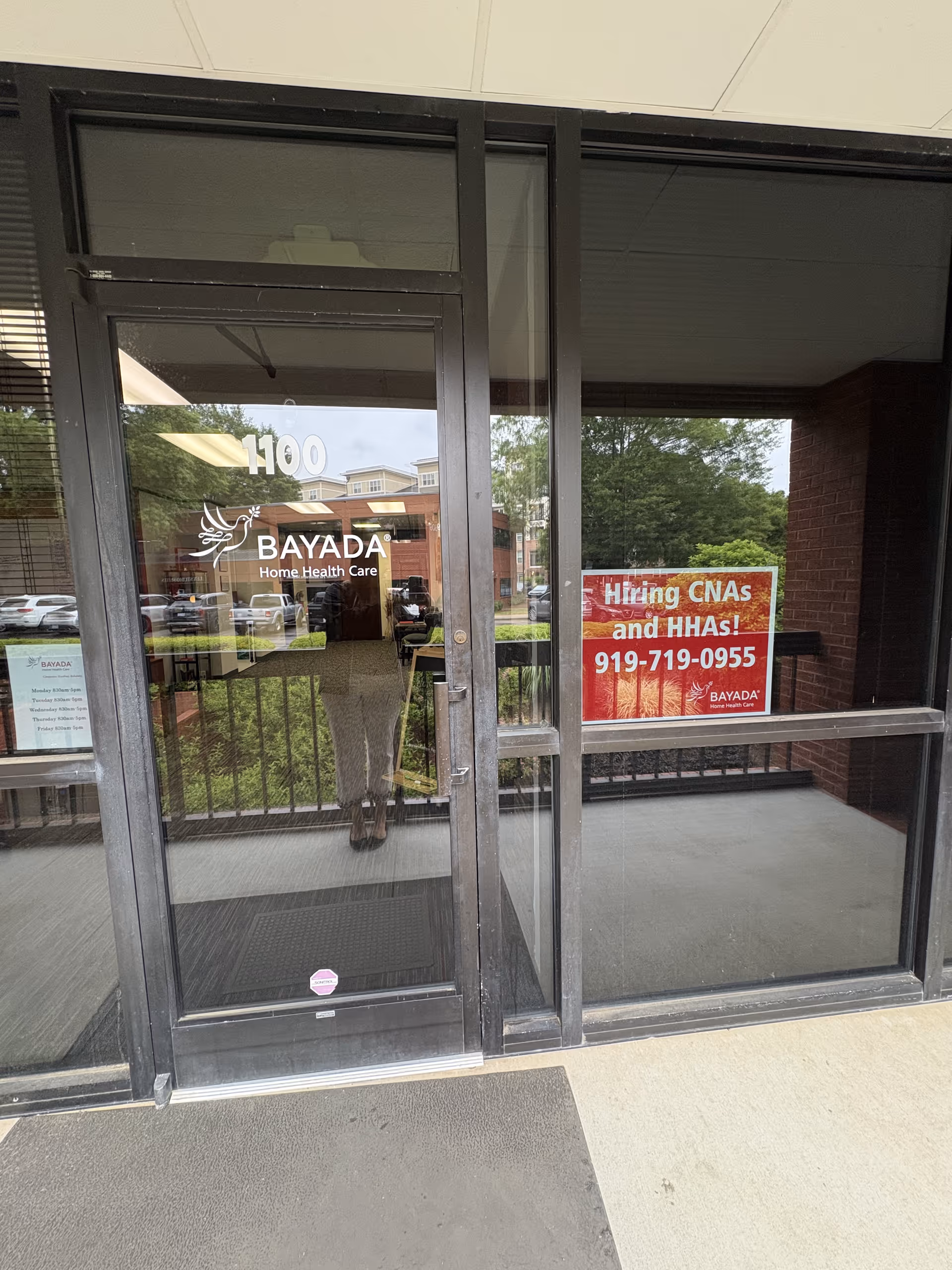 Glass entrance to BAYADA Assistive Care building with a hiring sign visible.