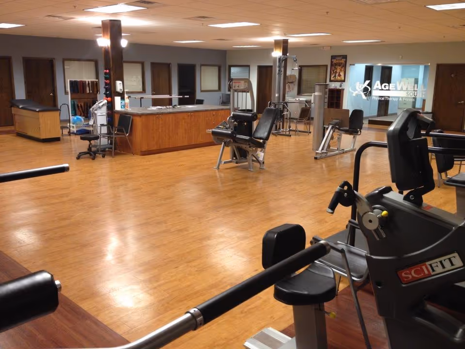 Open indoor fitness area at AgeWell with exercise machines and a reception desk.