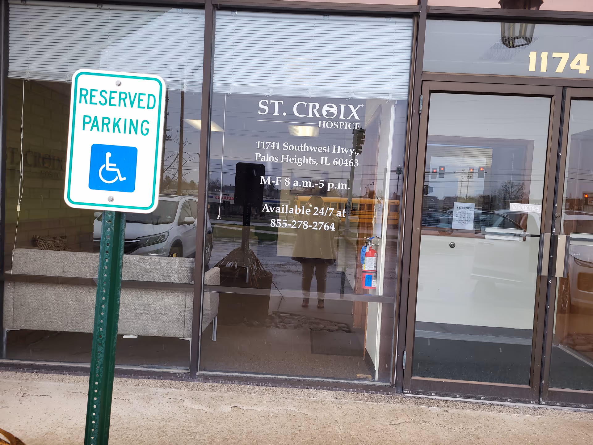 Front exterior of St. Croix Hospice with glass doors and a reserved parking sign.