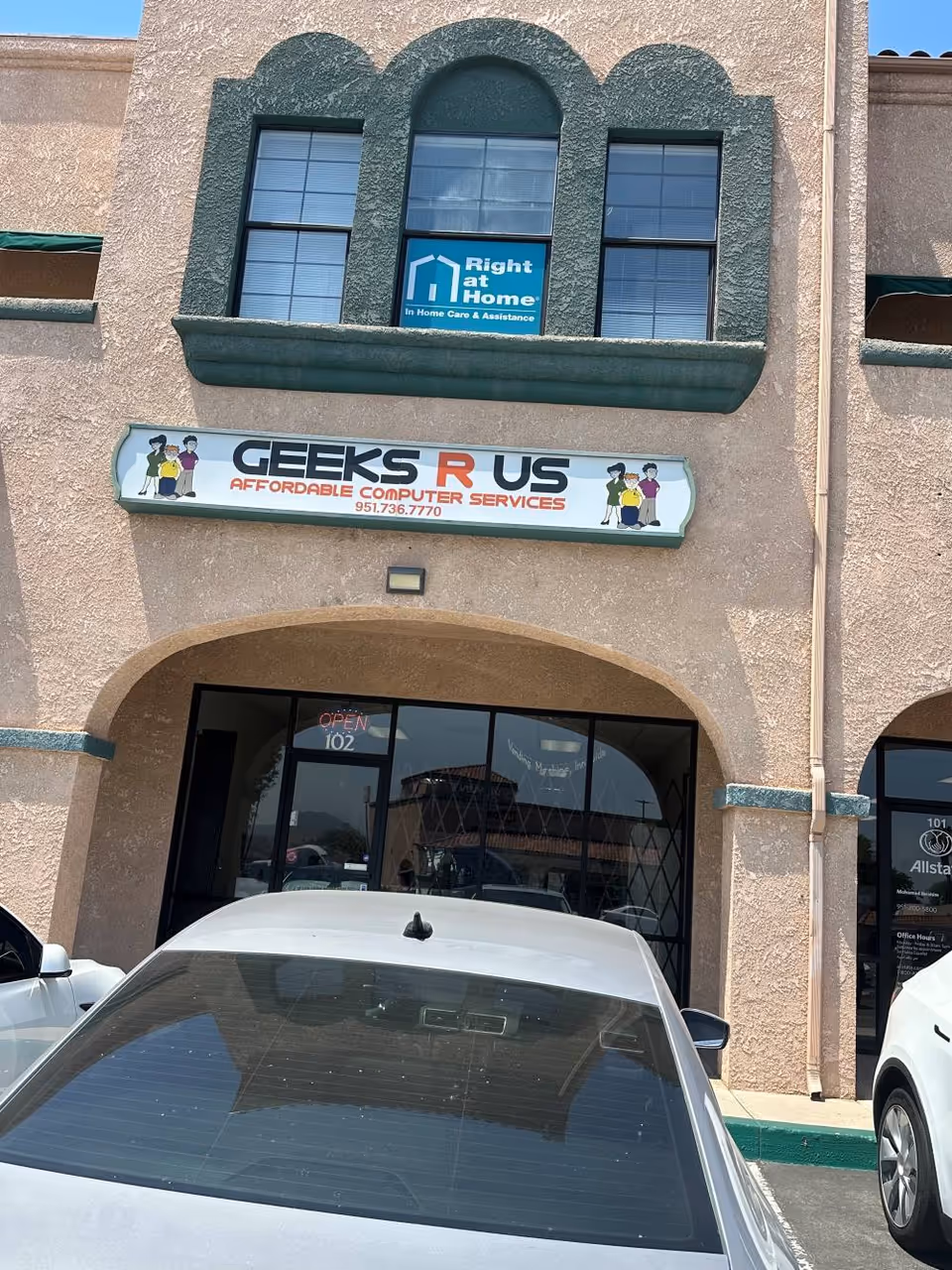 Exterior view of a beige building with Right at Home and Geeks R Us storefront signs.