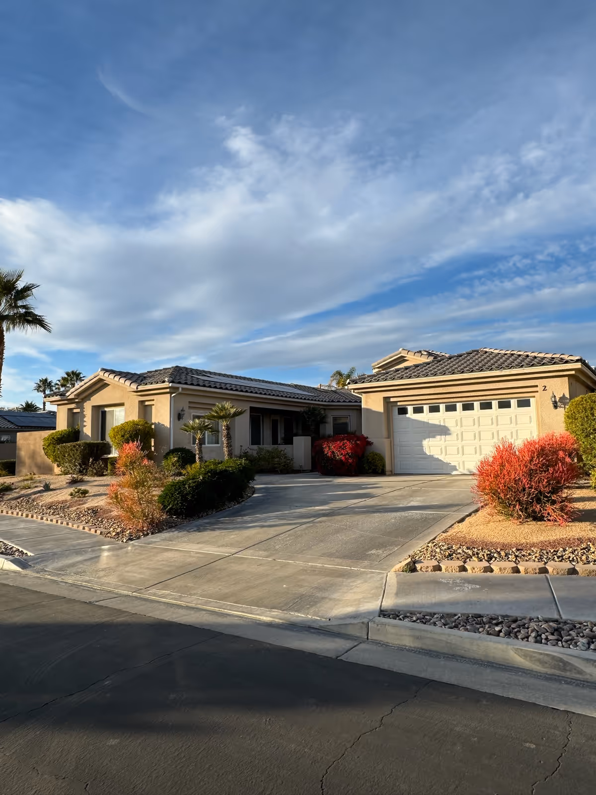 Exterior of AMPM Comfort Care facility: single-story building with driveway and desert landscaping.