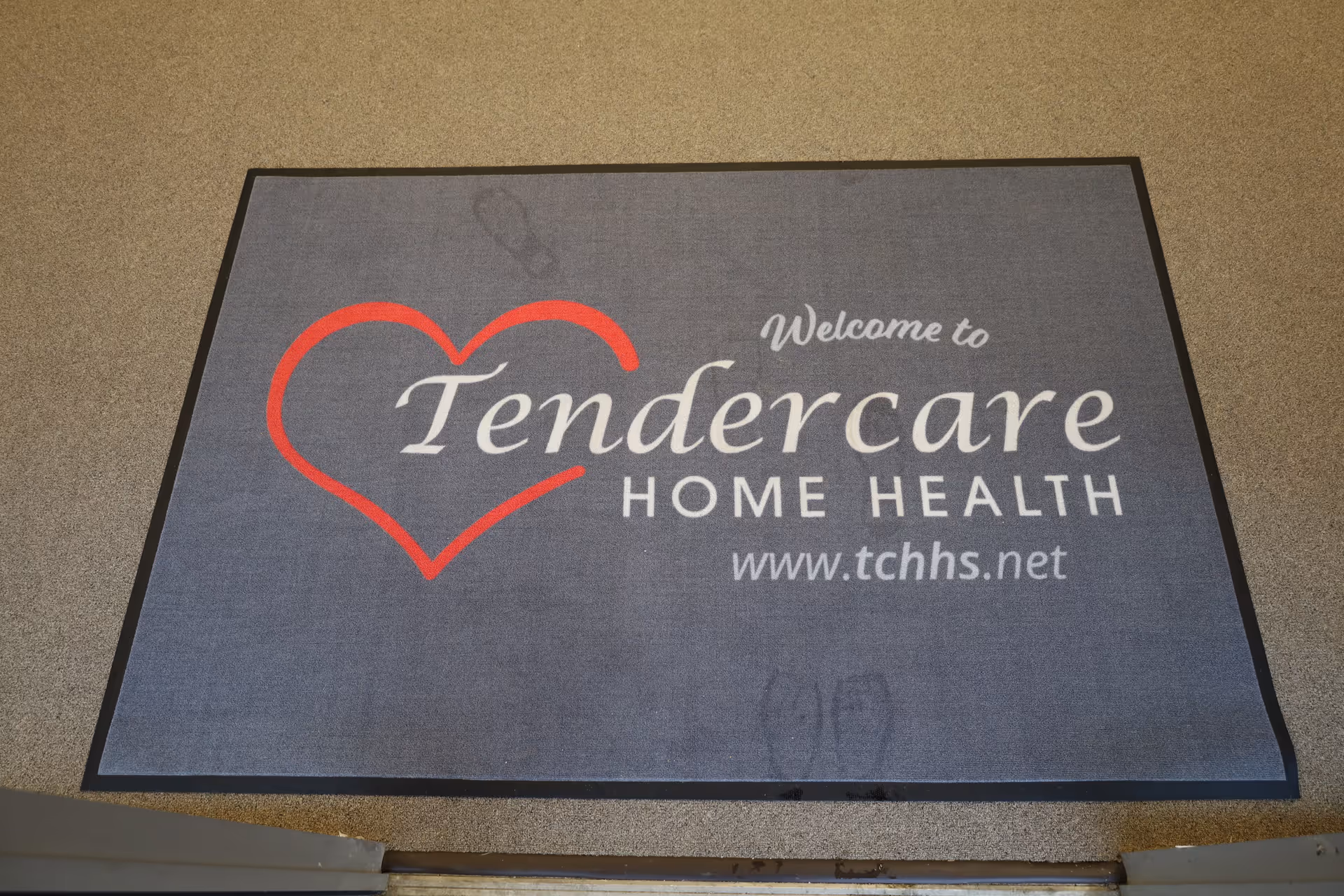 Entrance mat displaying Tendercare Home Health Services logo with heart design.