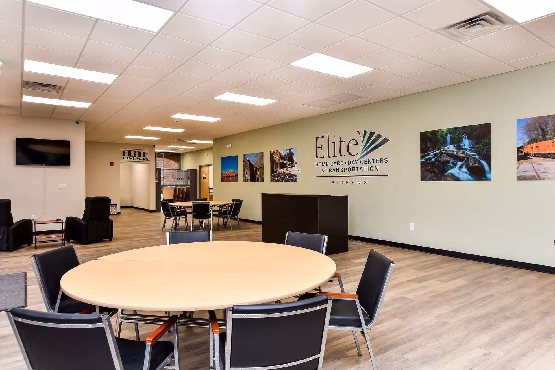 Interior common area with round tables, chairs, and Elite logo on the wall.