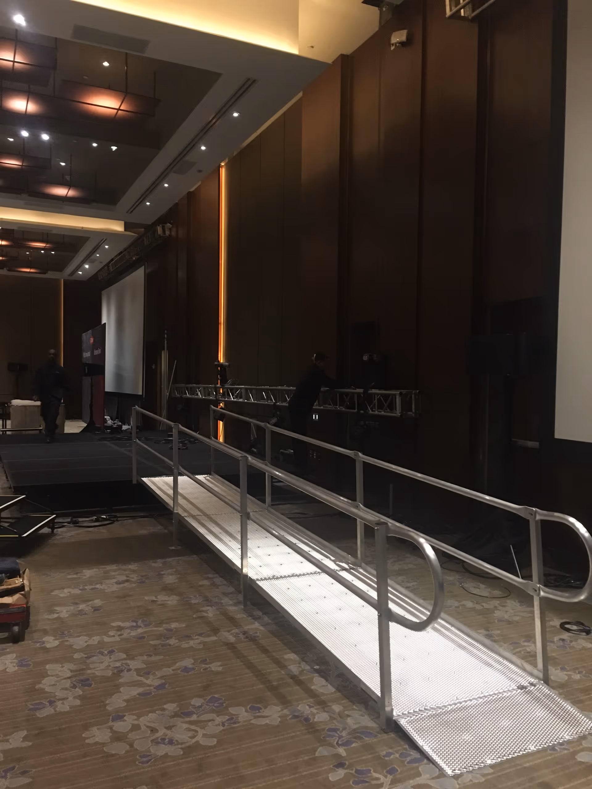 Indoor conference hall with a metal ramp leading to a stage and lighting.