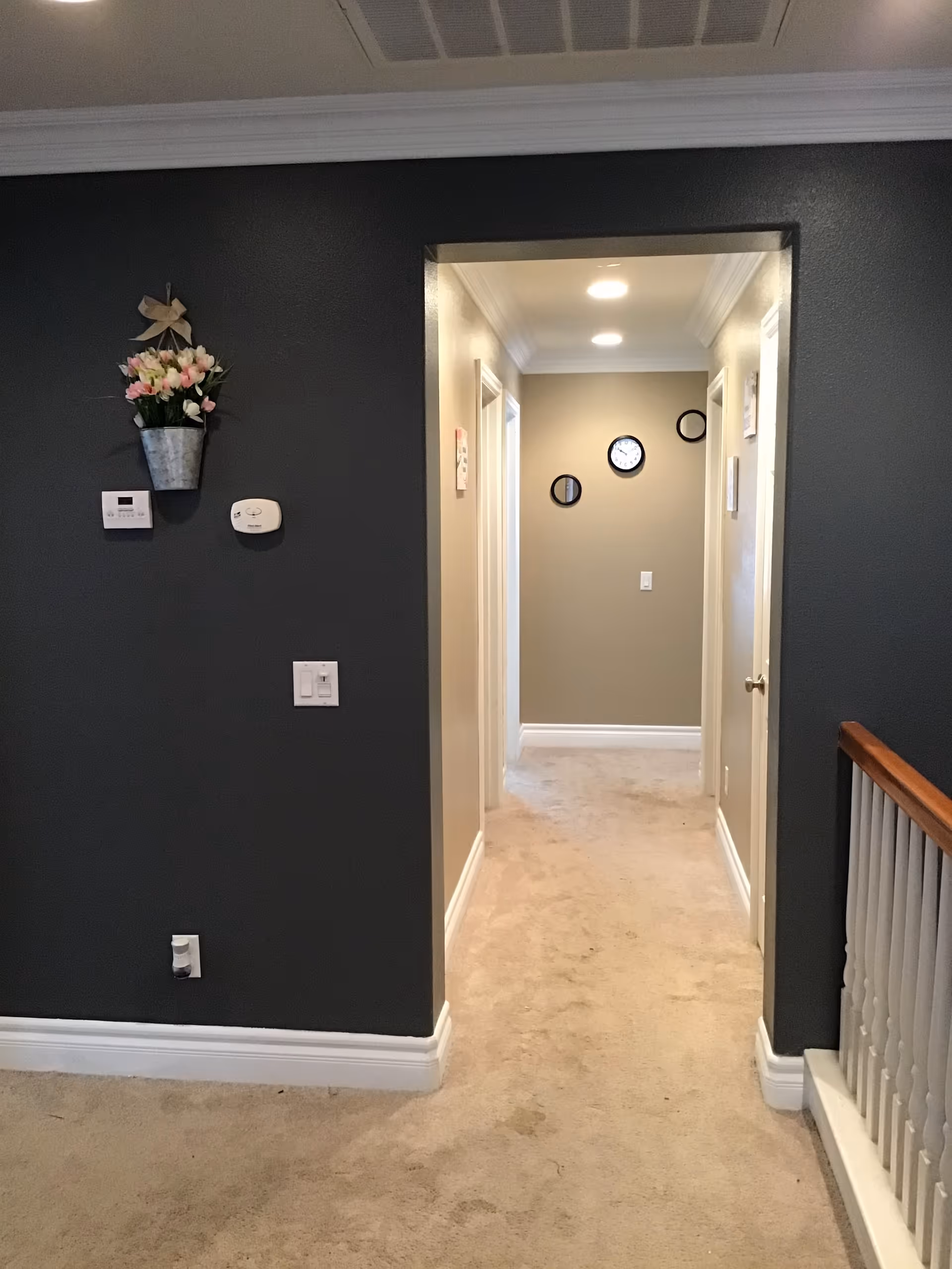 Narrow interior hallway of a senior living facility with wall clocks and decor.