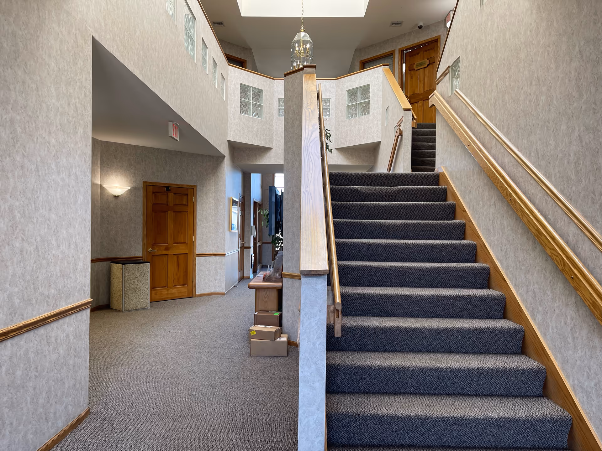 Interior stairwell with carpeted stairs, wooden railings, beige walls, skylight, and upper landing.