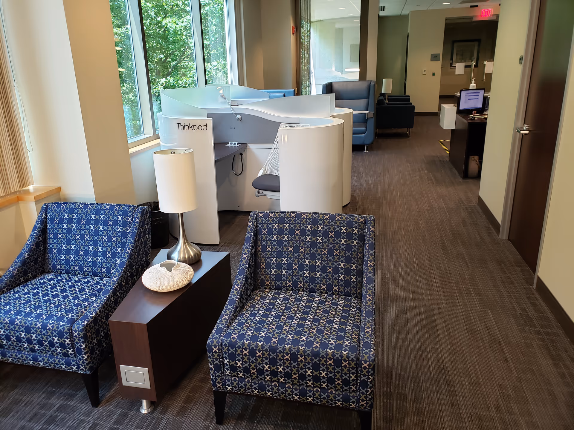 Modern interior lounge in a senior facility with blue patterned chairs and a curved white desk.