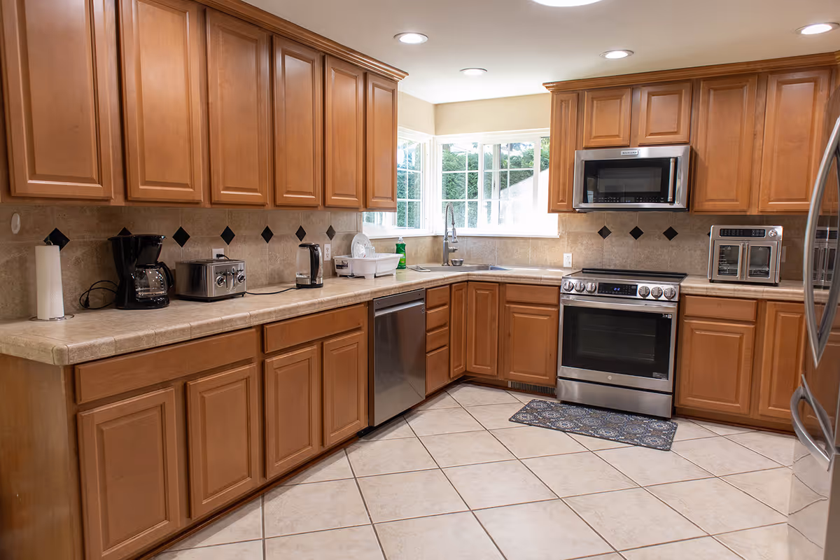 U-shaped kitchen with wooden cabinets, tile floor, and stainless steel appliances.