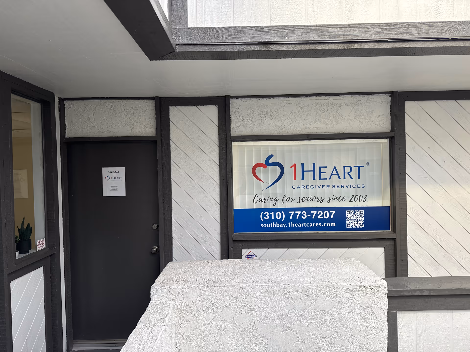 Entrance to a building with 1Heart Caregiver Services sign in window.