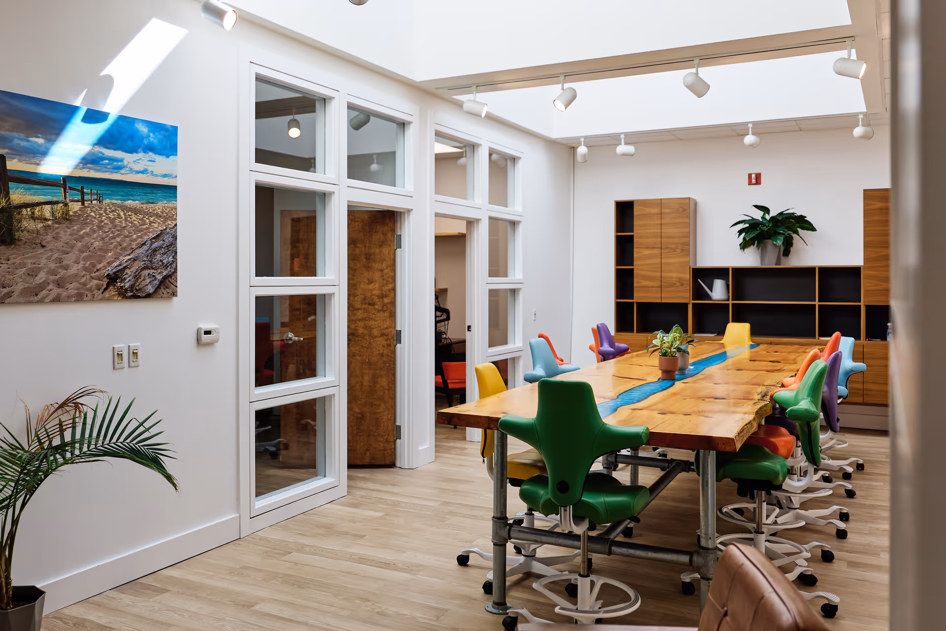 Bright modern dining room with a long wooden table and colorful chairs.