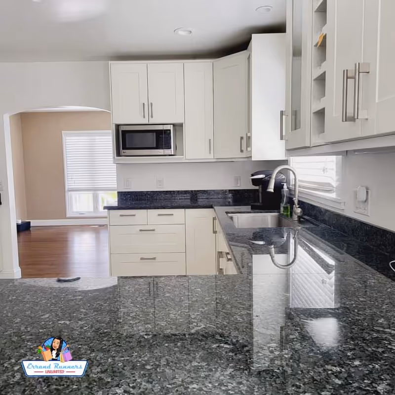 Bright white kitchen with granite counters, sink, microwave, and ample cabinetry.
