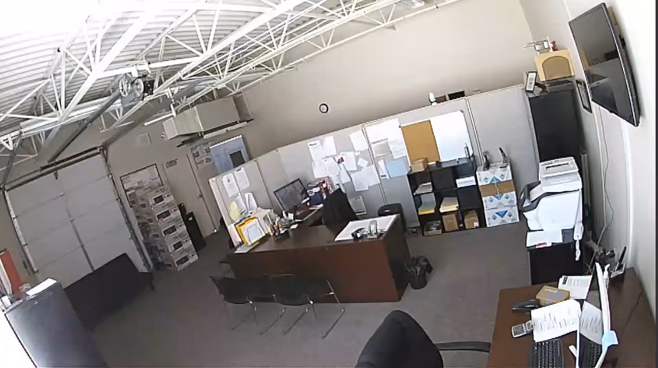 Office admin area with desks, chairs, filing shelves, printers, and bulletin boards.