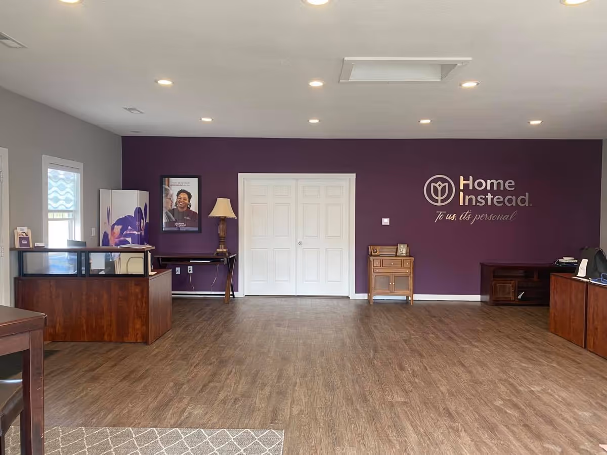 A spacious lobby with purple accent wall, reception desk, and Home Instead logo.