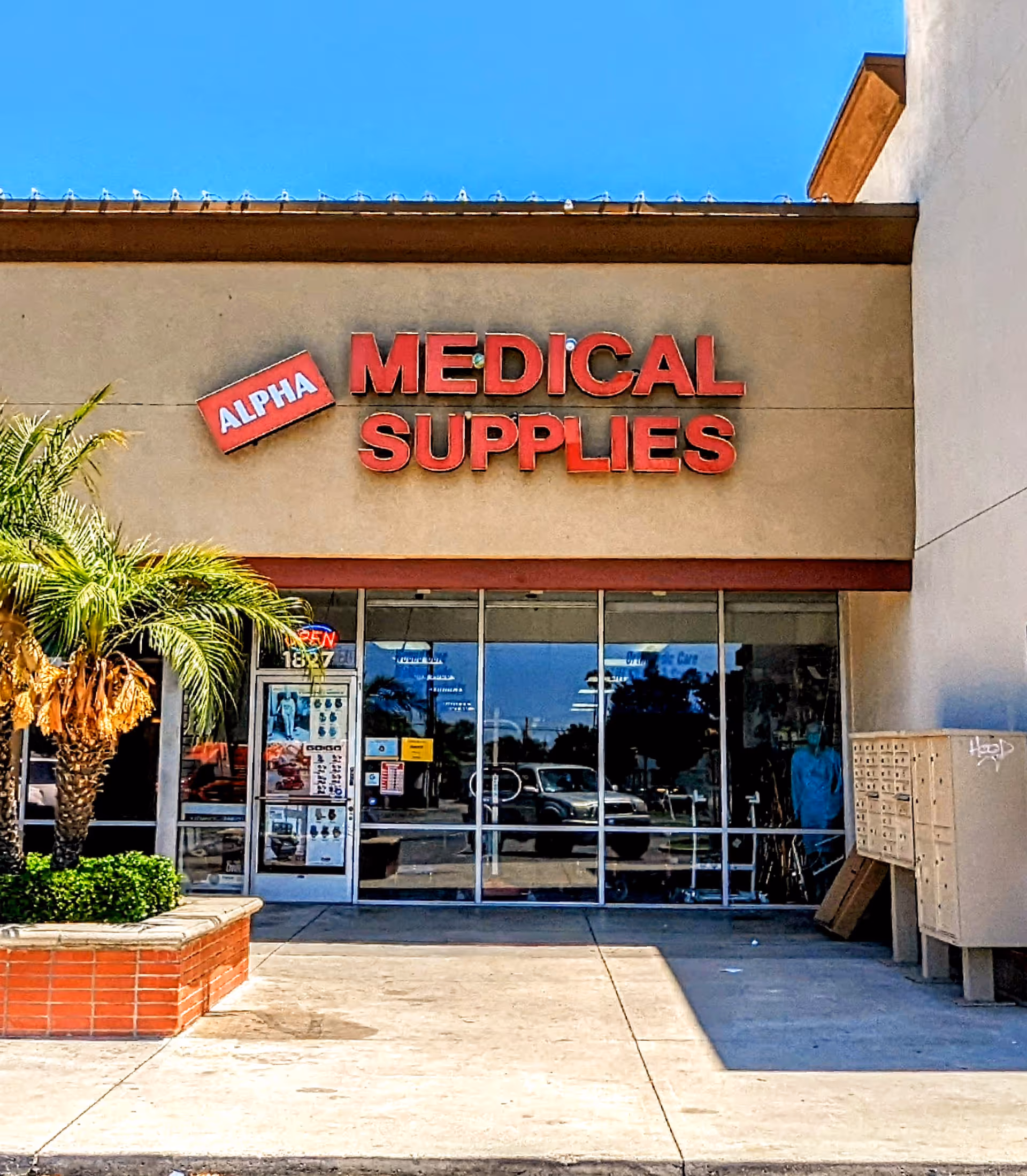 Front exterior of Alpha Medical Supplies store with glass entrance and bold red sign.