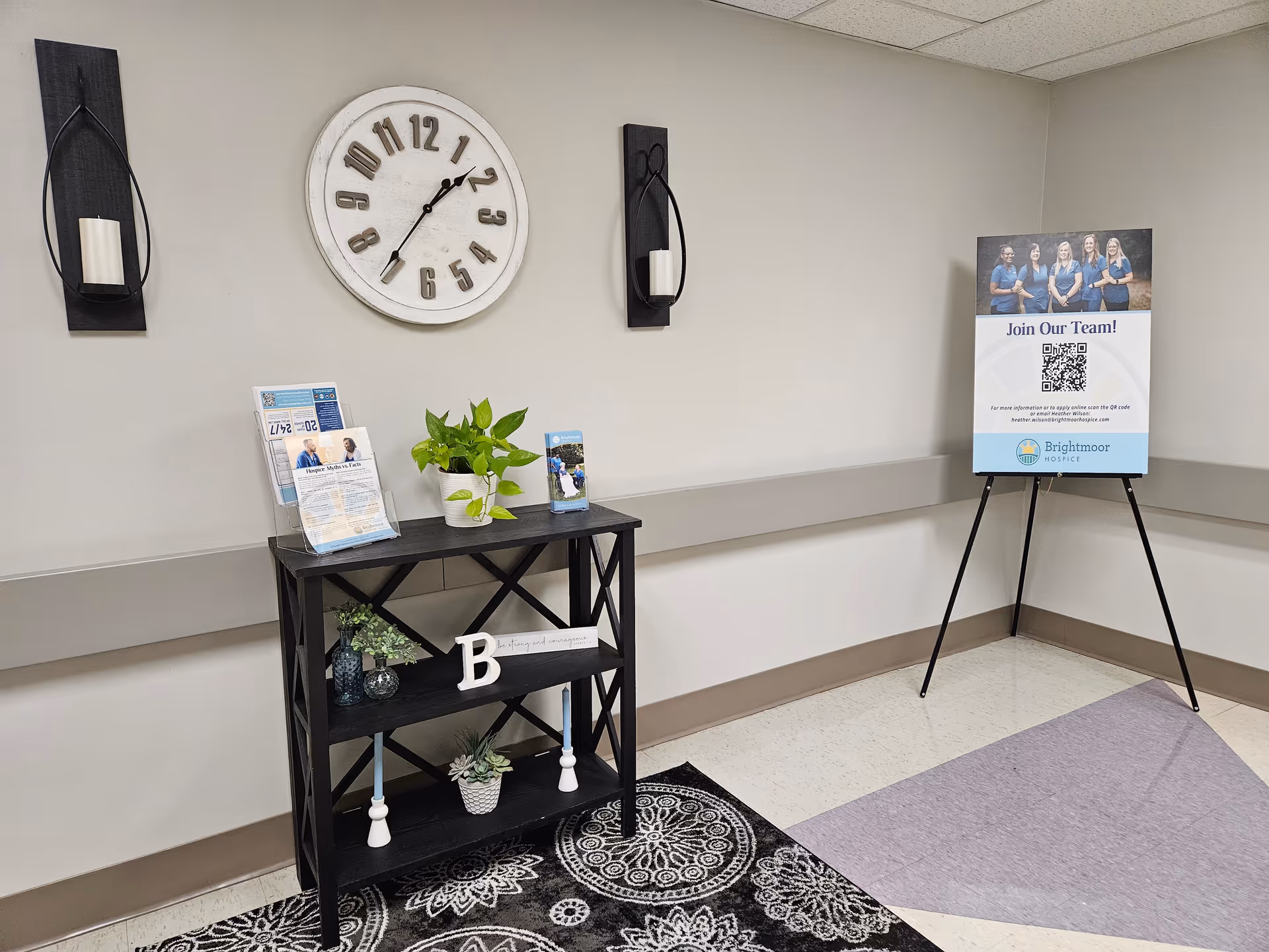 Interior lobby area with clock, console table, plants, and job sign on easel.