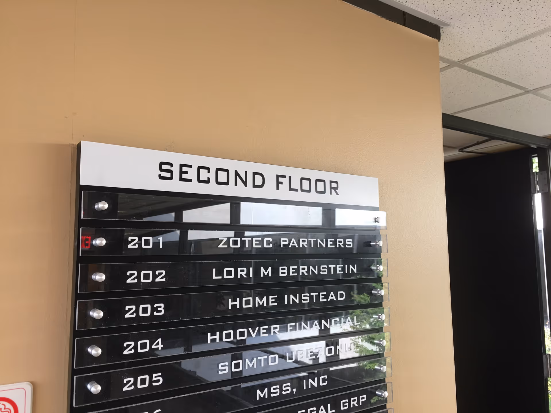 Beige interior wall with 'Second Floor' sign and office plaques listing suites.