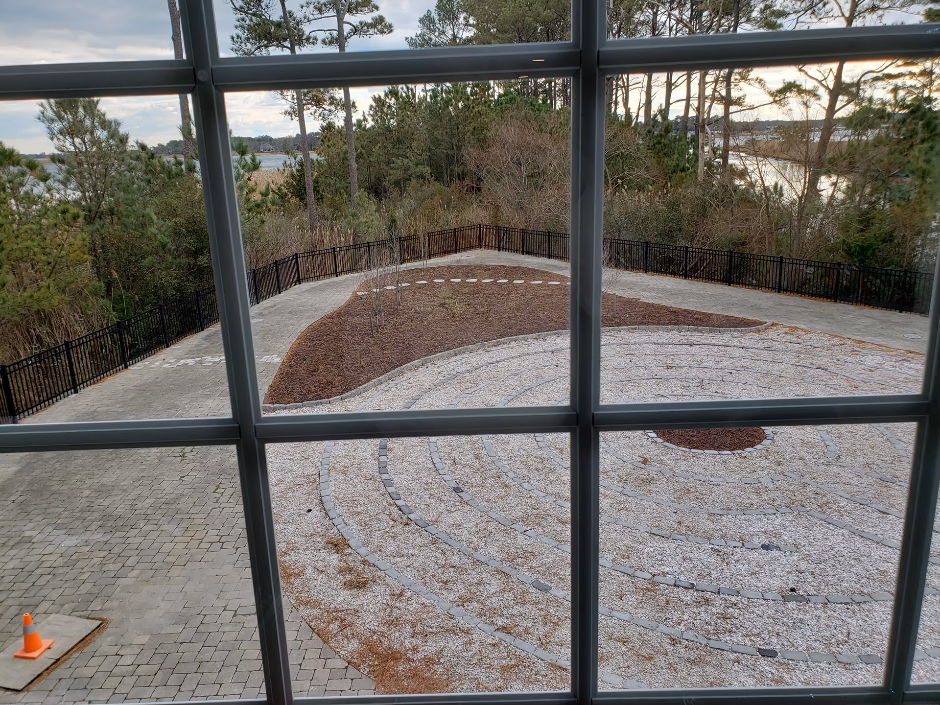 View through large windows onto an outdoor circular courtyard with gravel and surrounding trees.