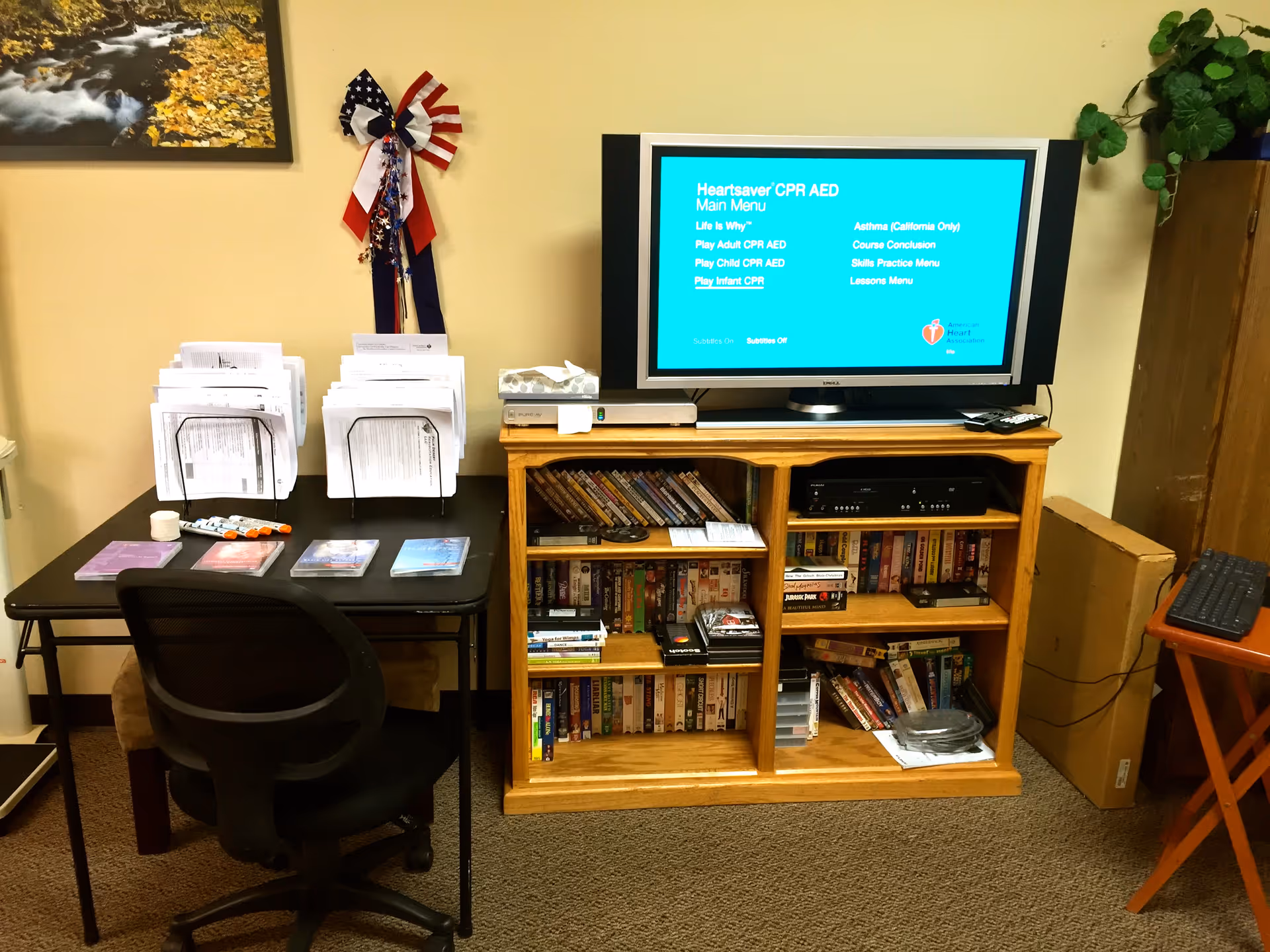Small indoor office area with desk, chair, and TV on a wooden media cabinet.