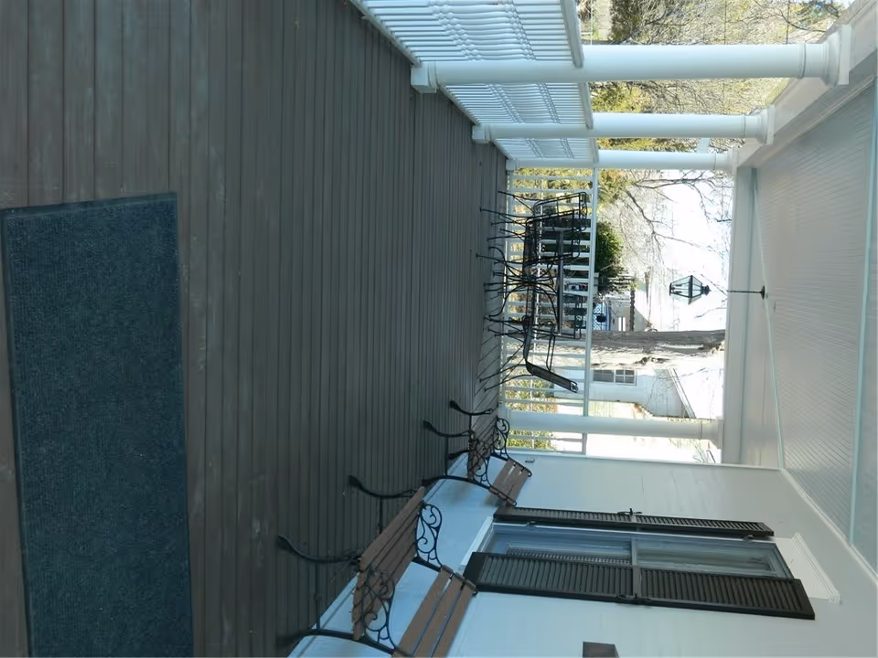 Exterior covered porch of The Historic Holly House Office Suites with stacked chairs.