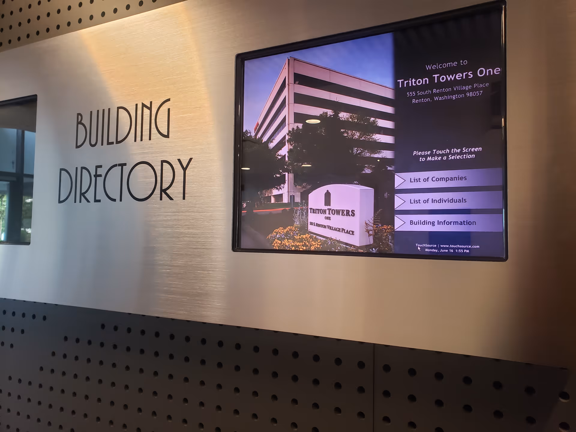 Interior wall featuring a large BUILDING DIRECTORY sign next to a digital information screen.