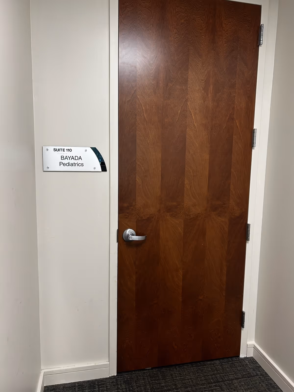 Interior hallway with a wooden door labeled Suite 110 BAYADA Pediatrics.