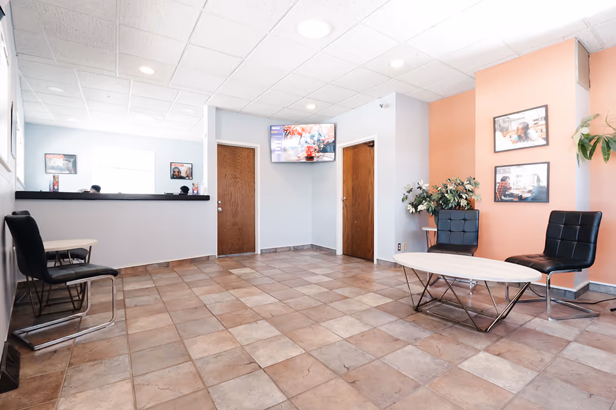 Lobby waiting area in a senior facility with seating, a reception desk, and doors.