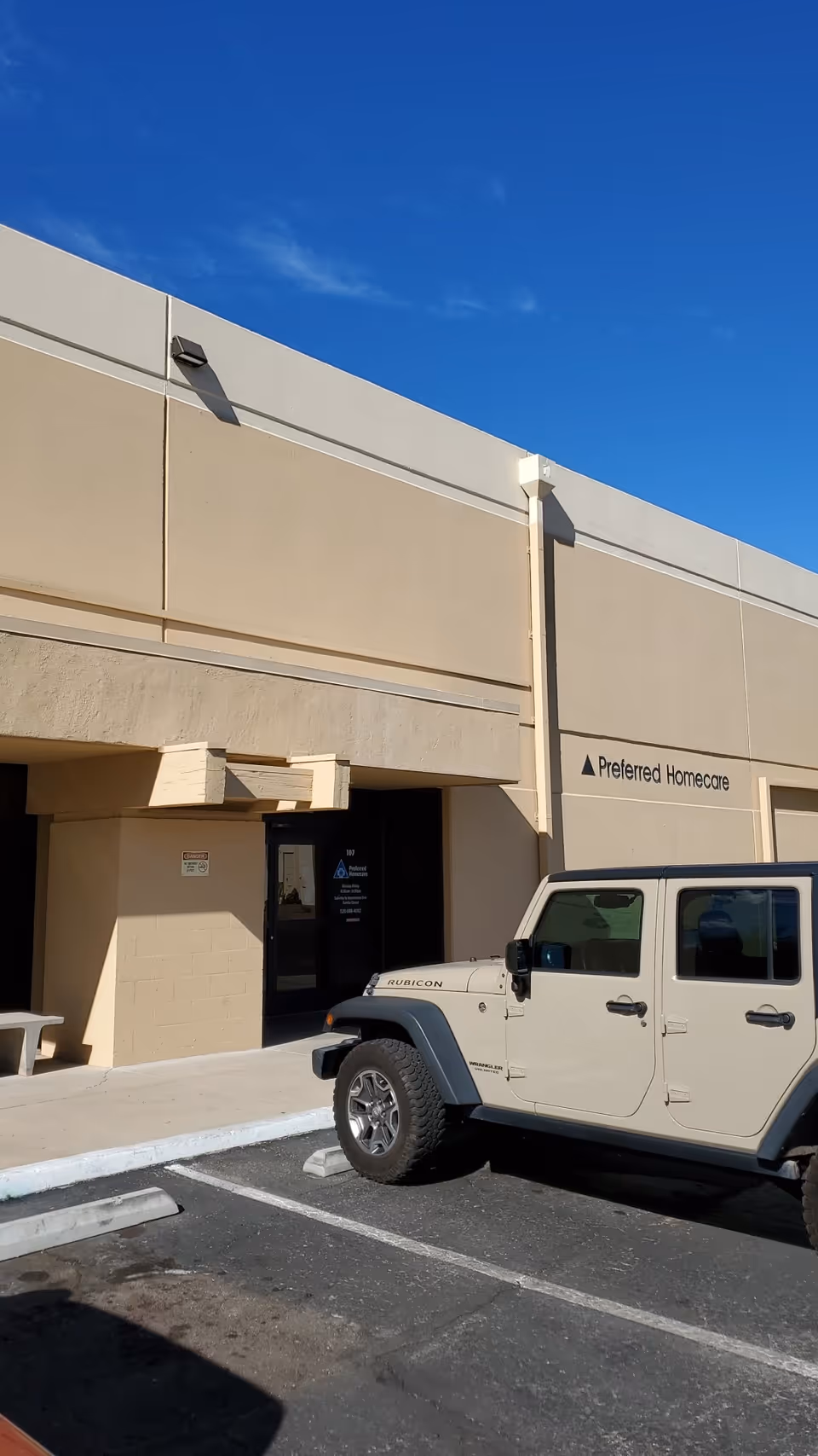 Exterior view of Preferred Homecare facility with beige walls and a parked white Jeep.