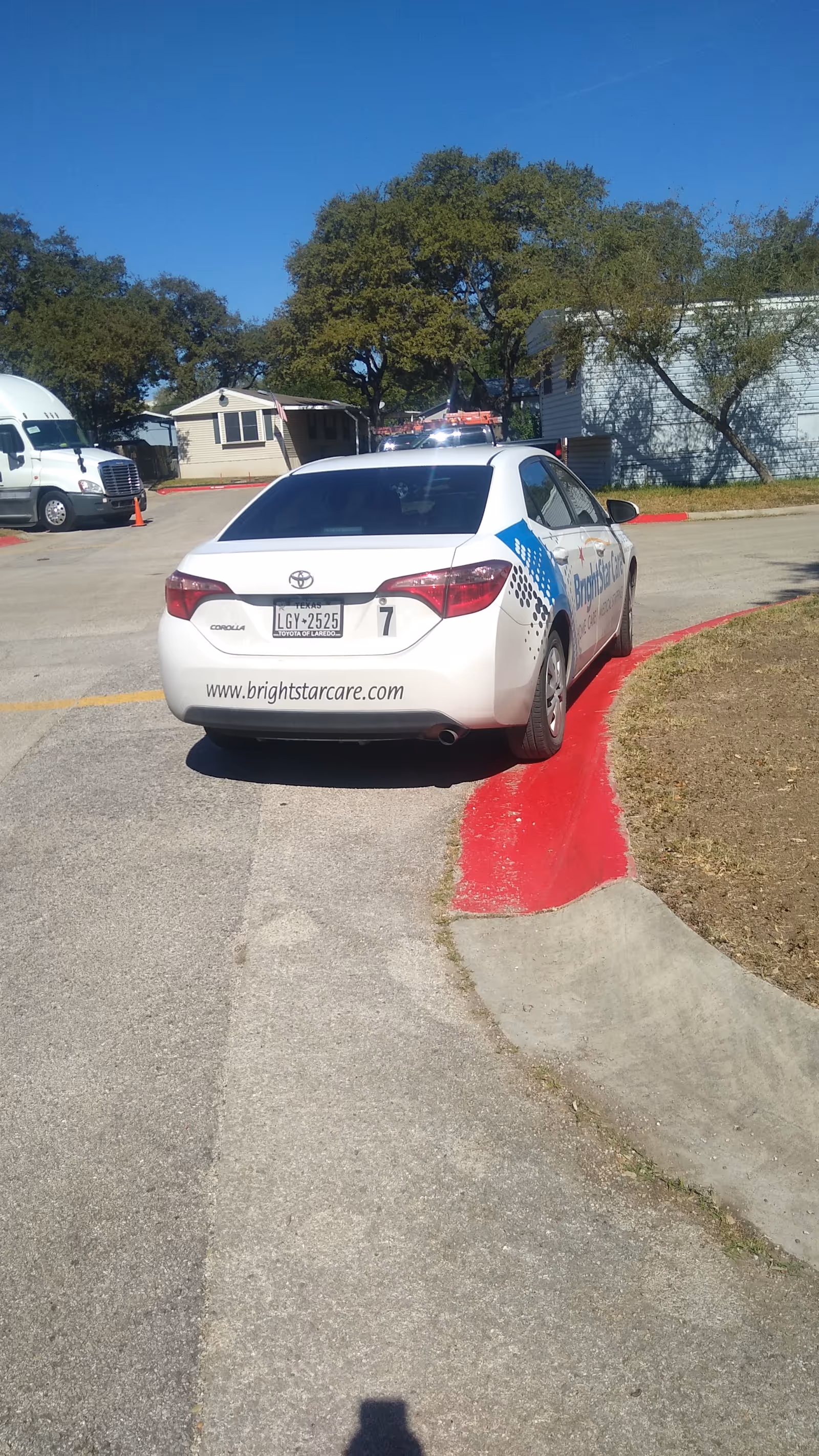 White BrightStar Care car parked in a lot near a building with trees