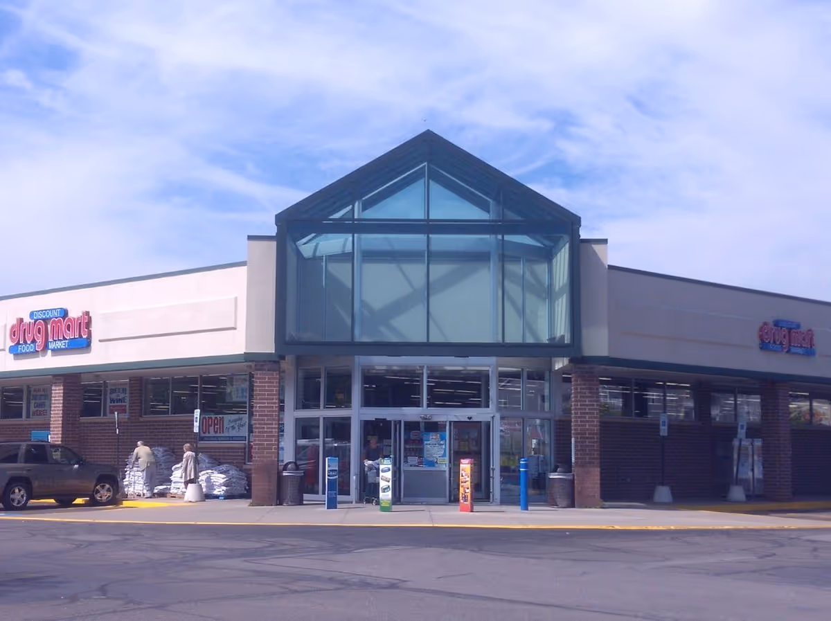 Front view of Discount Drug Mart store with glass entrance and sky.