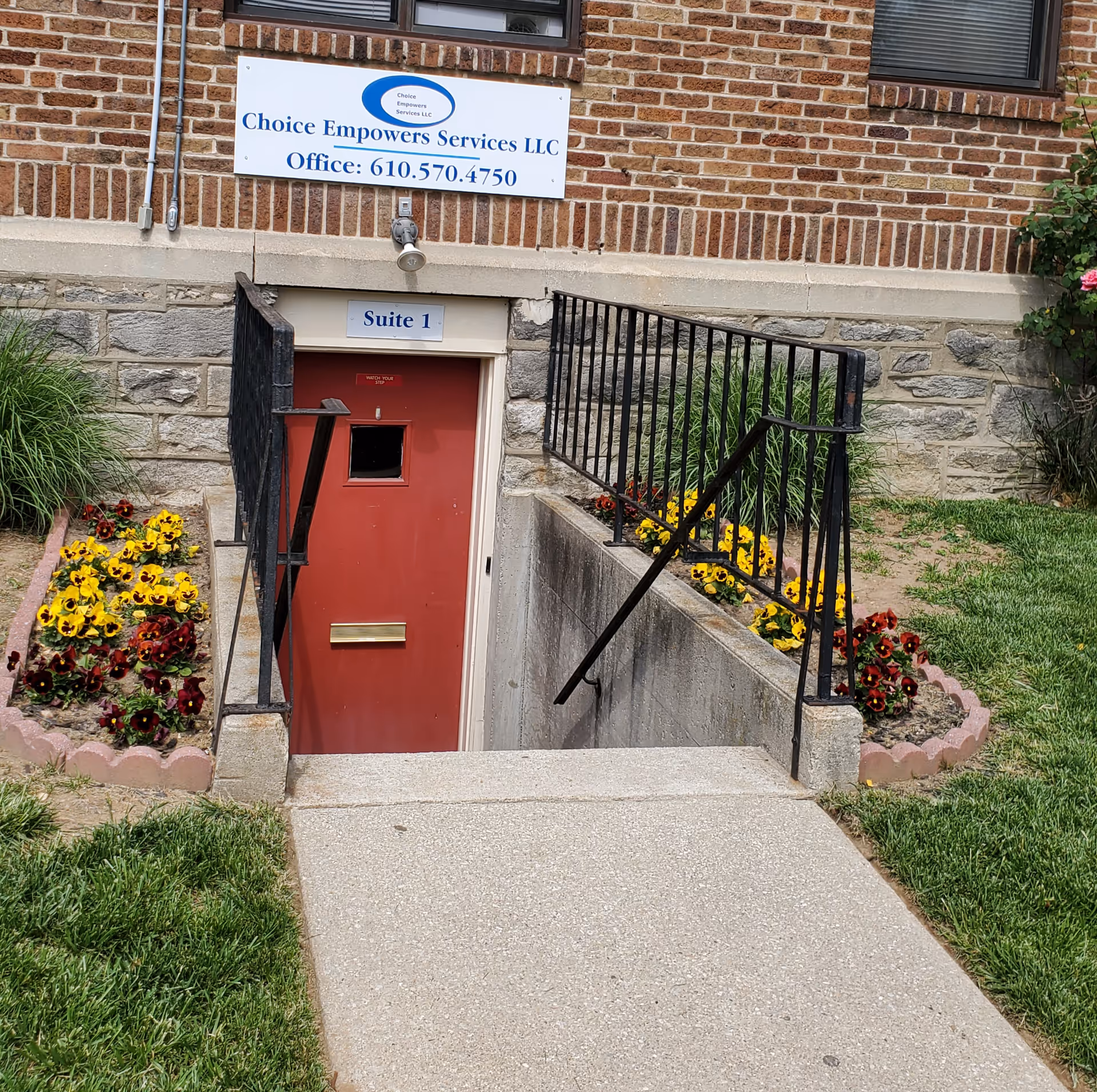 Brick building exterior showing Choice Empowers Services LLC sign and red basement door.