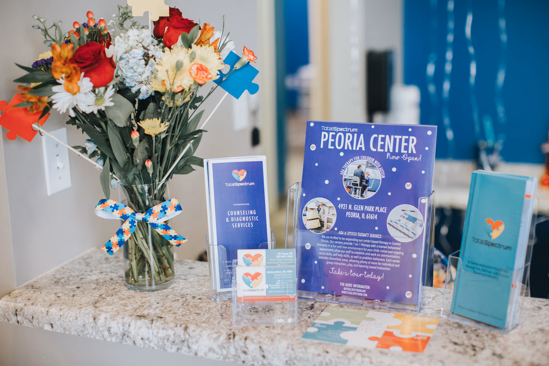Reception counter with a vase of flowers and informational brochures in a facility lobby.