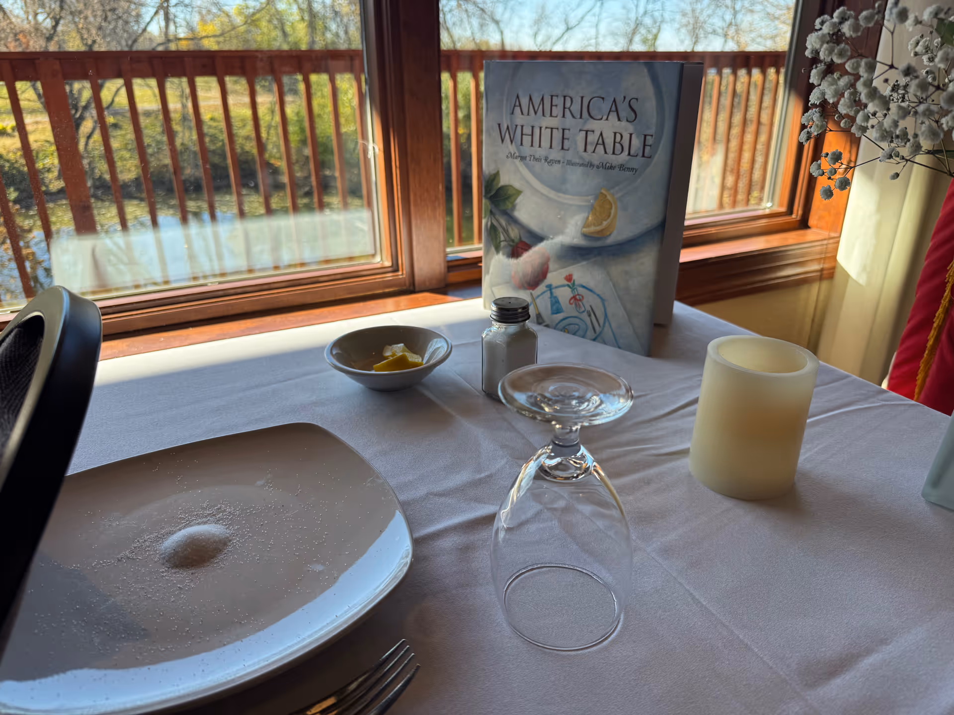 A dining table by a window with a sign reading America's White Table.